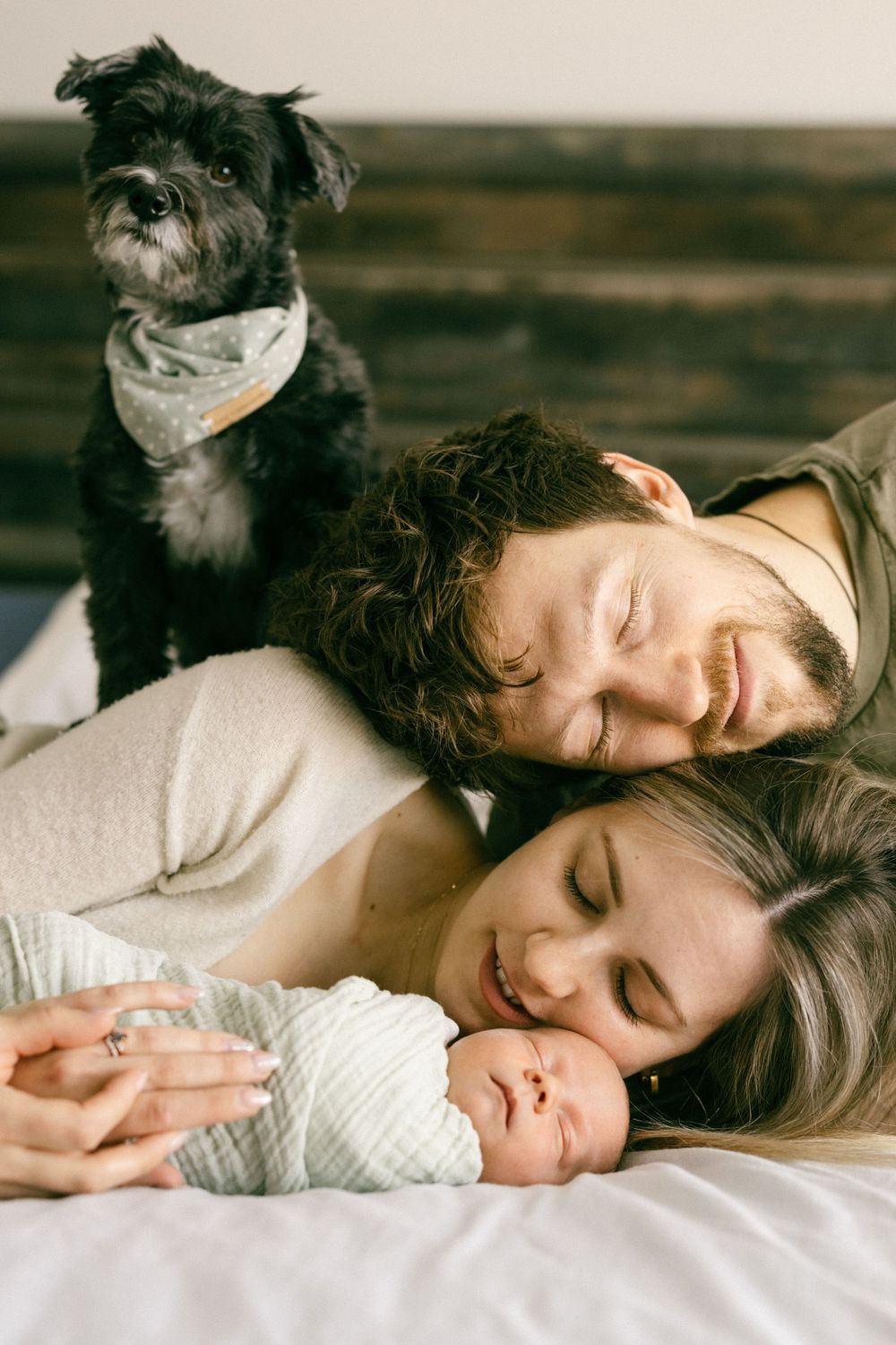 Intimate family moment captured on bed in warm natural lighting.