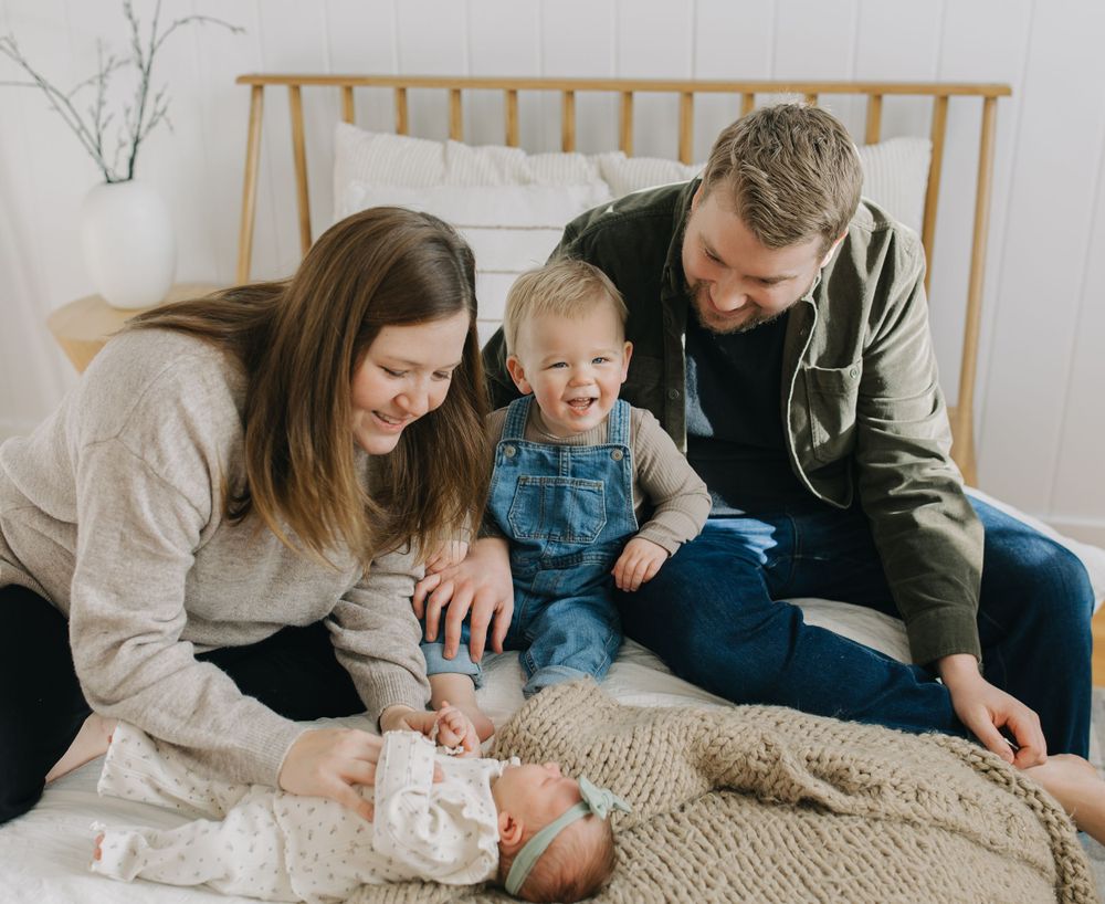 Family relaxing together on a textured rug in a cozy bedroom setting.