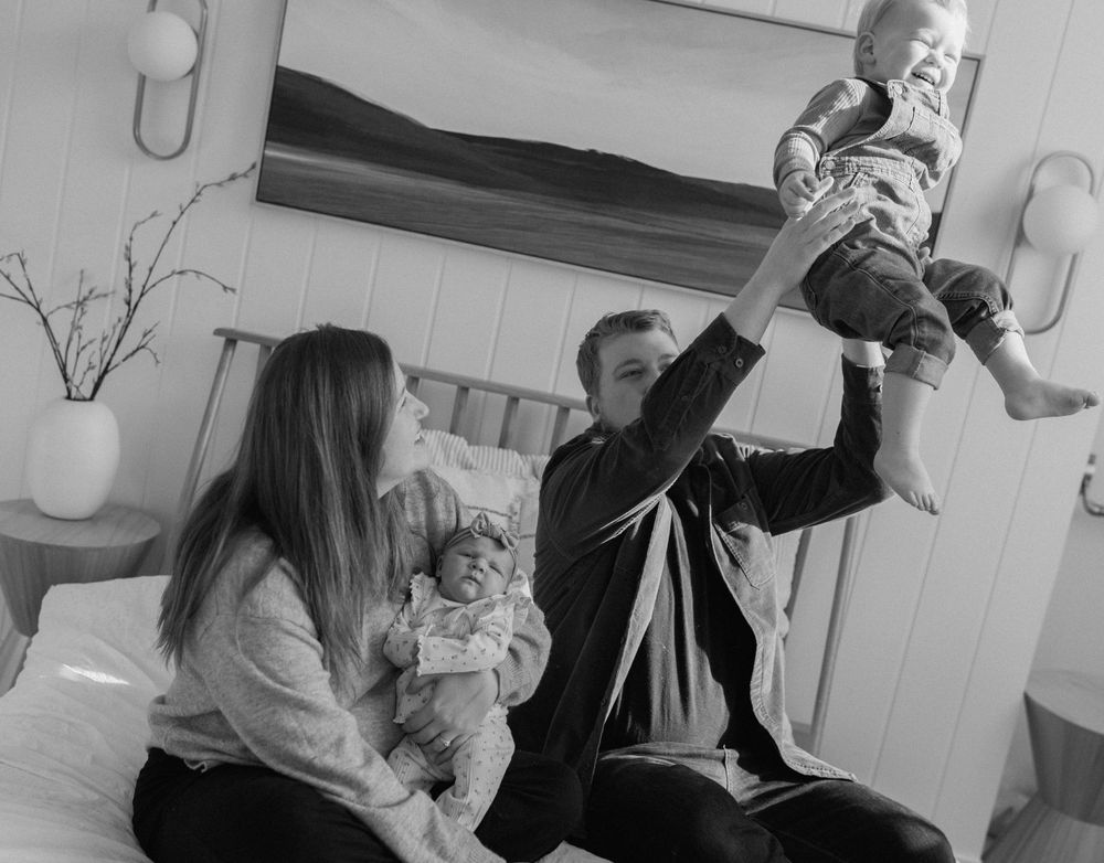 Playful family moments captured in black and white on a comfortable bed.