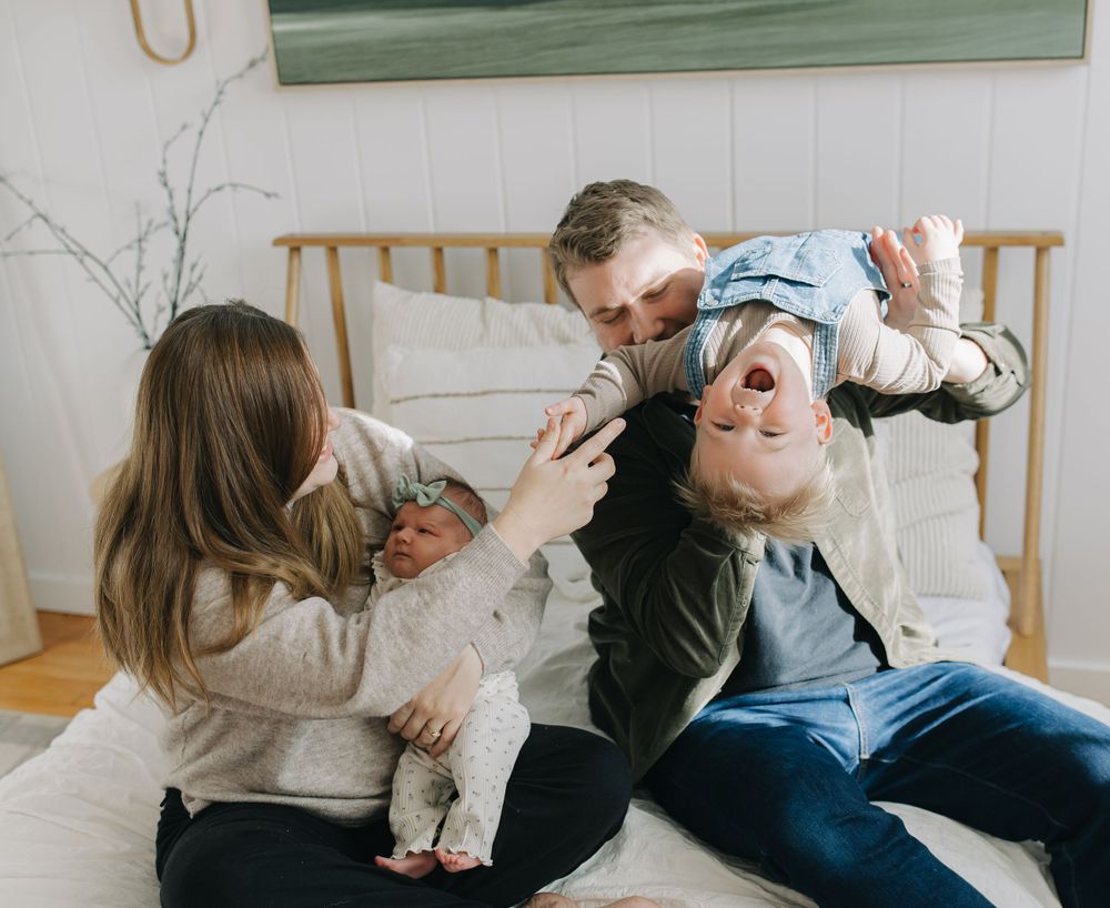 Series of intimate family moments photographed in a bright, minimal bedroom setting.