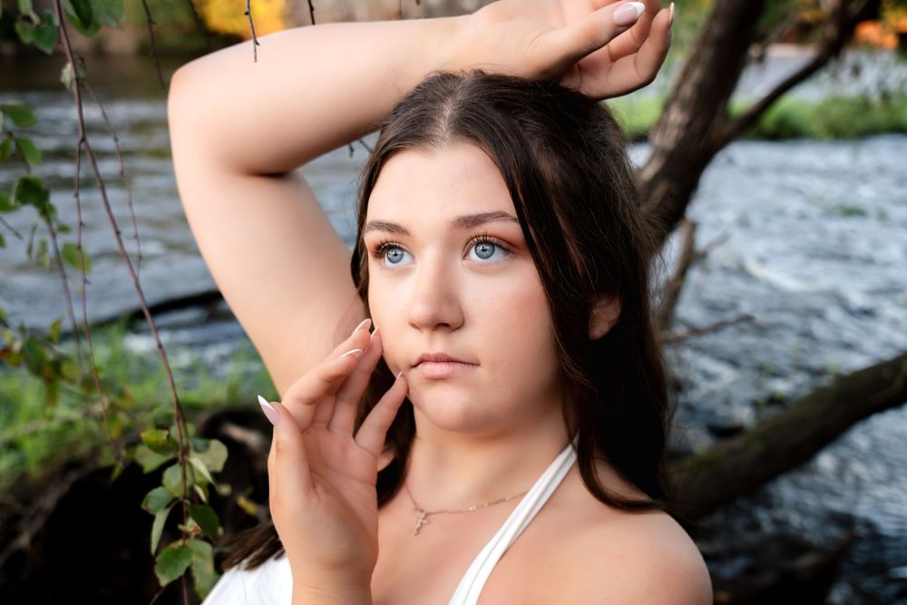 Riverside portrait session with warm evening light filtering through trees.