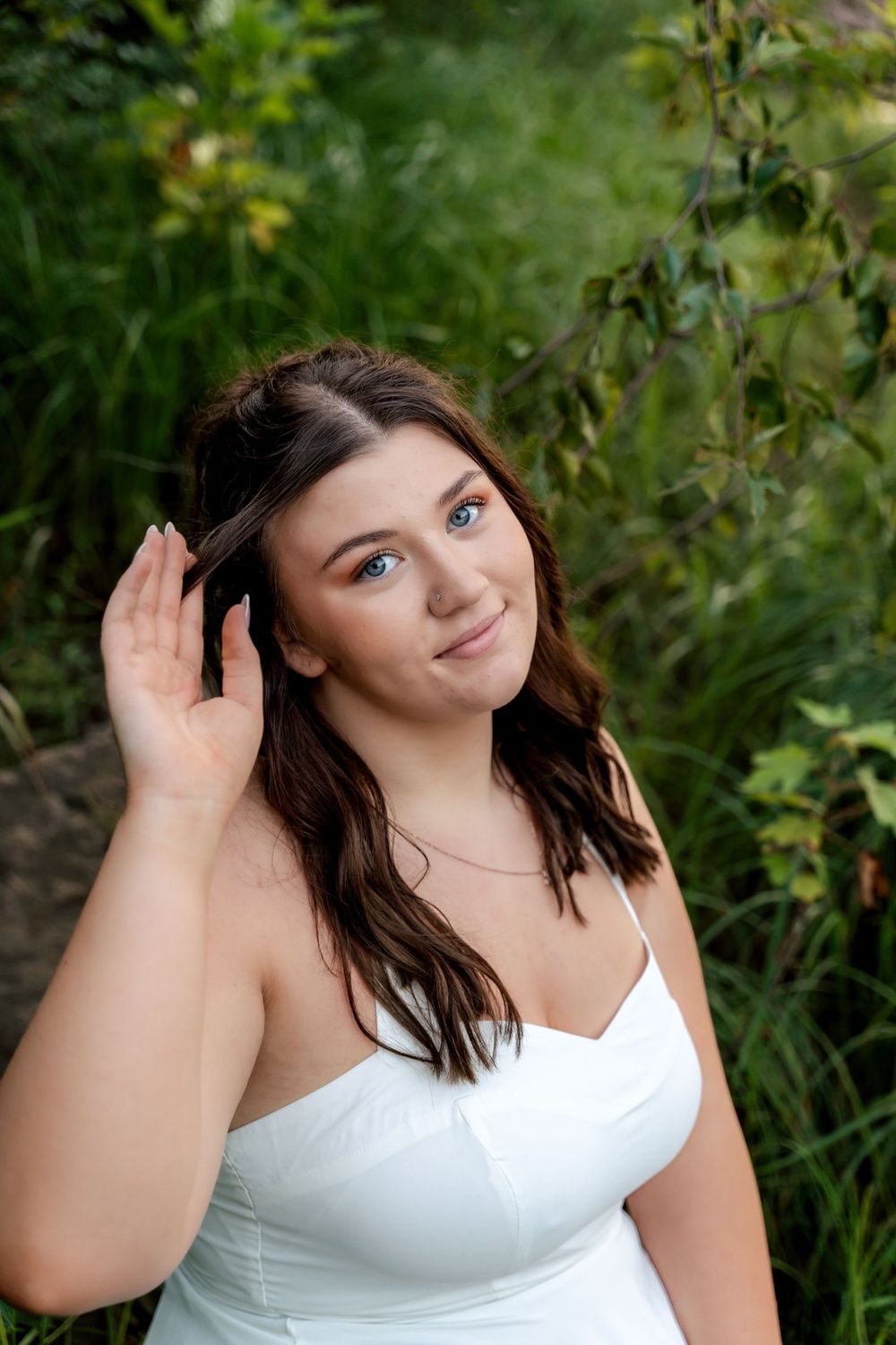 Summer portrait session in white against lush green foliage background.
