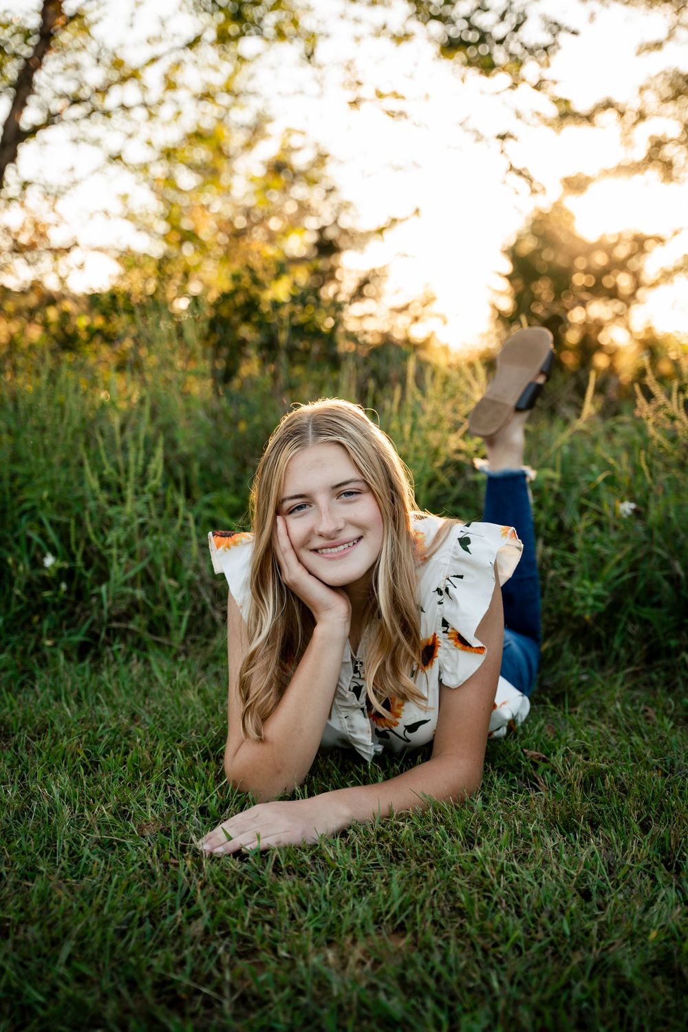 A person lying in green grass during golden hour photography session.