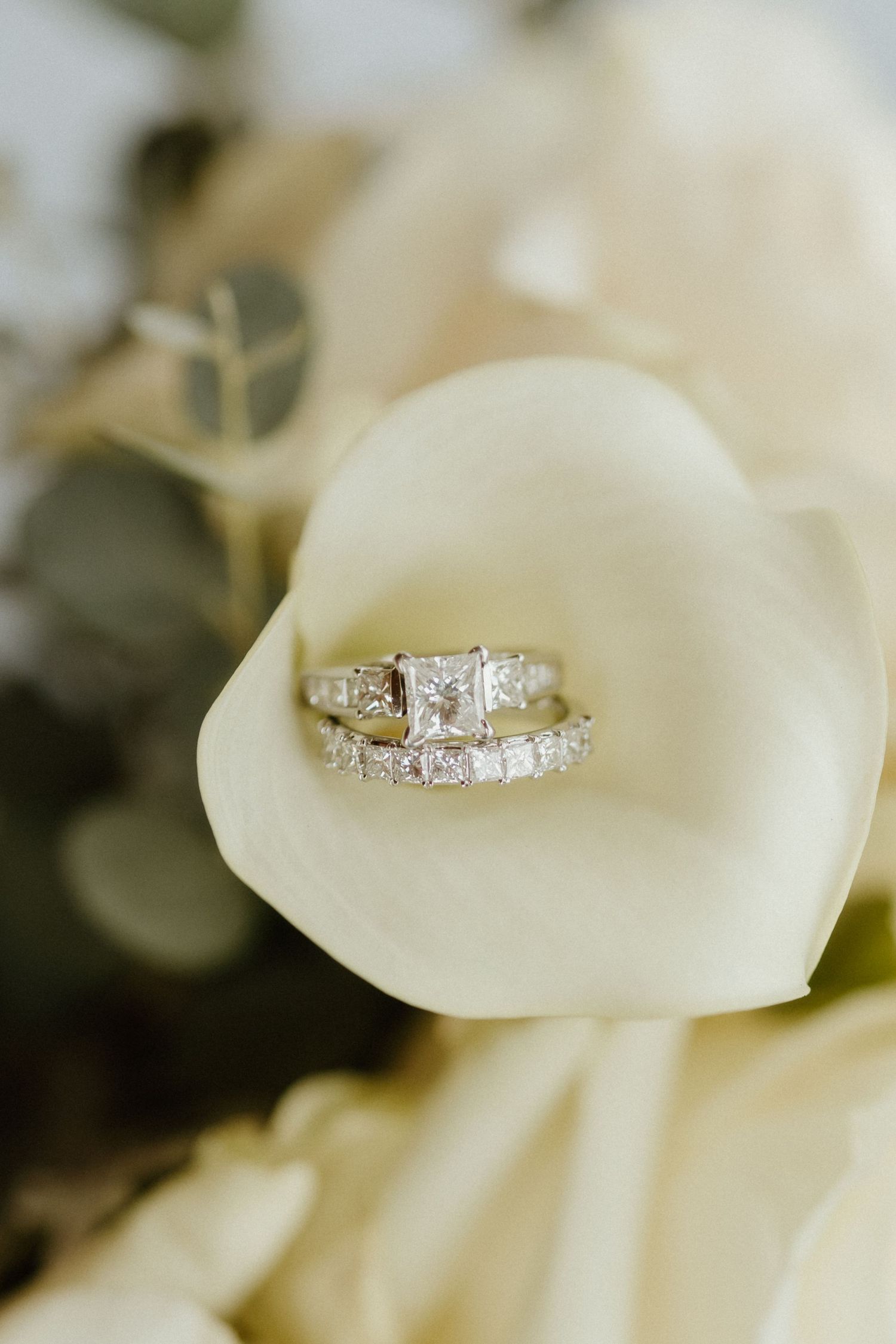 Diamond engagement ring and wedding band nestled in a white calla lily flower.