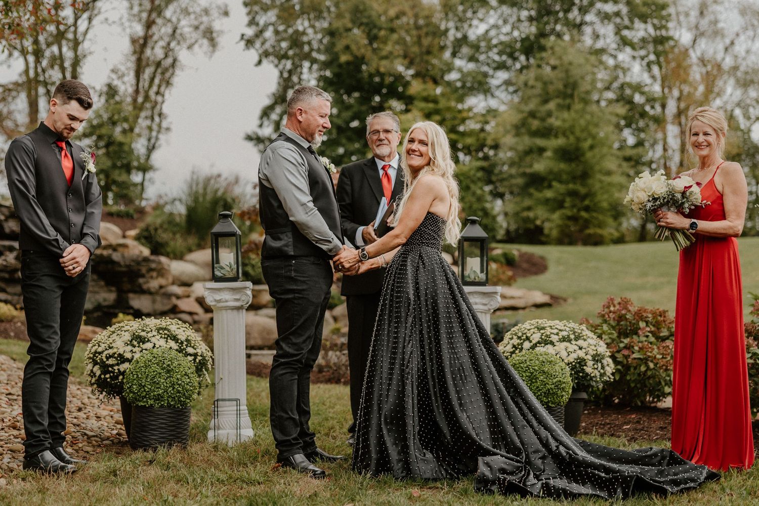 An outdoor wedding ceremony takes place in front of a rock waterfall garden.
