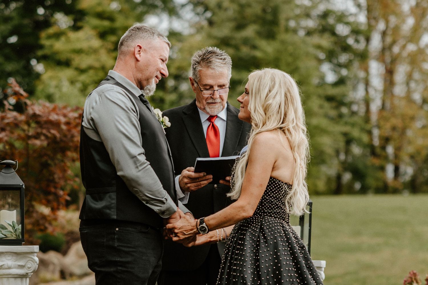 An intimate wedding ceremony being conducted in a garden setting with autumn foliage.