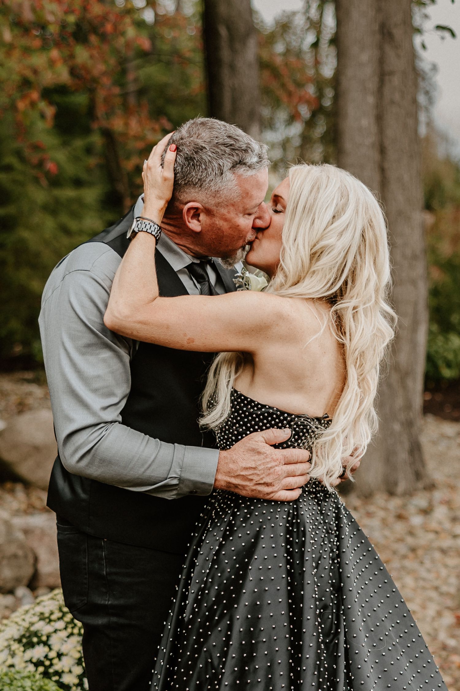 A romantic moment captured during an outdoor autumn wedding celebration.