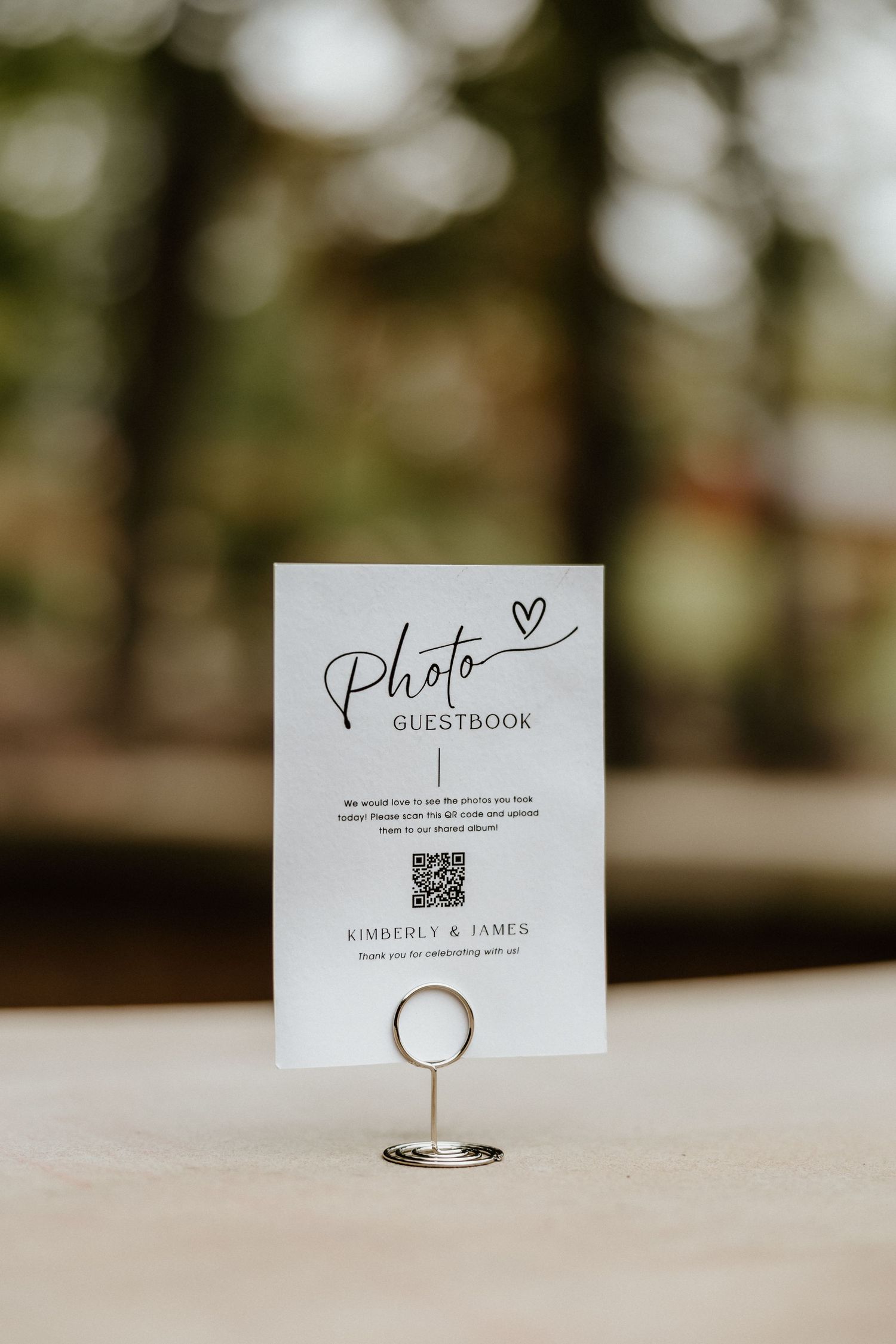 A wedding photo guestbook sign displayed on a silver stand with QR code.