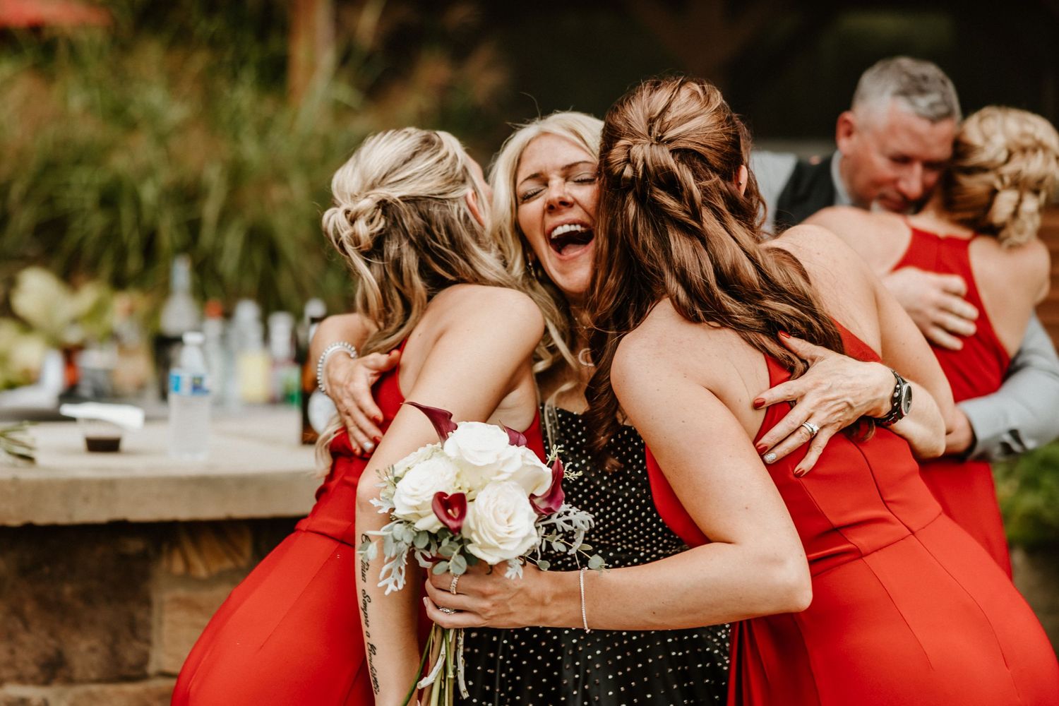 Joyful celebration with bridesmaids in bright red dresses holding bouquets.