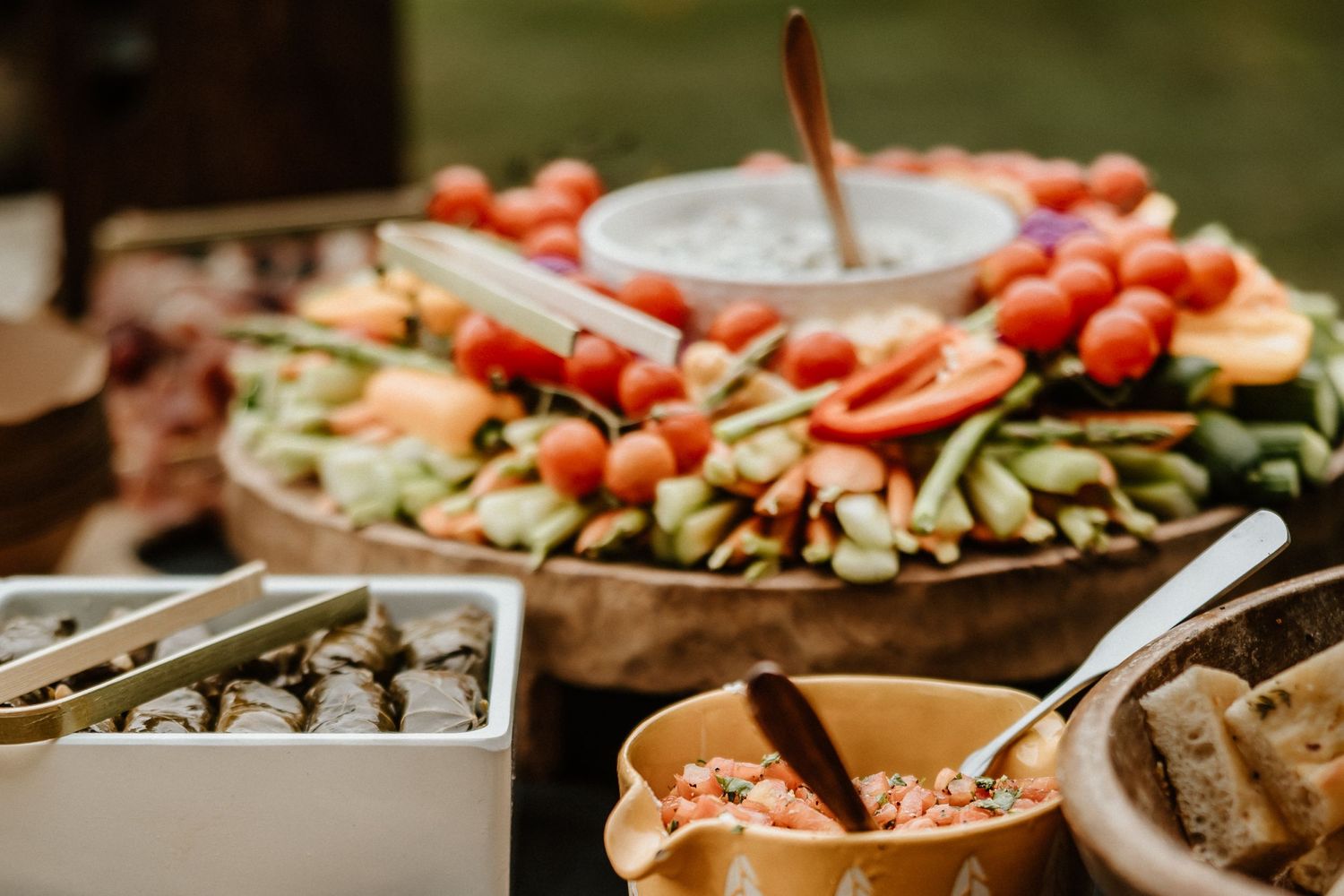 Fresh vegetable crudites and appetizers arranged on wooden serving platters at an event.