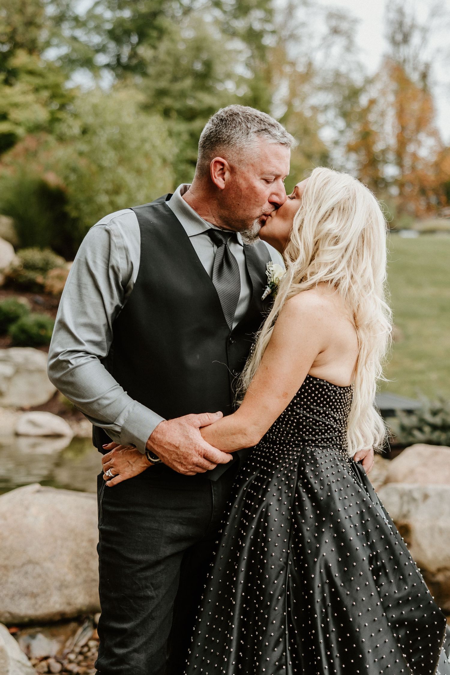 Romantic moment between couple in formal attire against autumn foliage background.