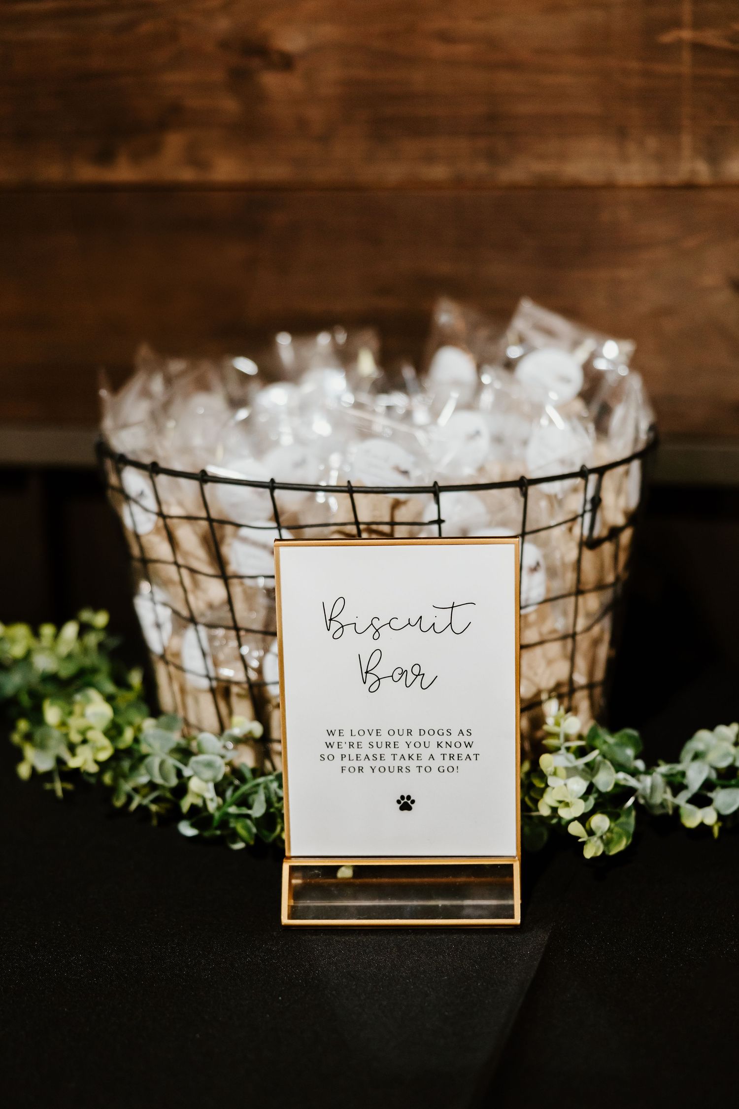 Rustic wire basket with biscuit bar sign and greenery decorations at wedding reception.
