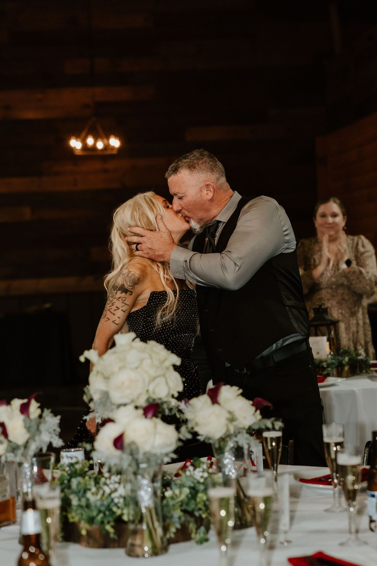 Romantic moment captured during wedding reception with candlelit tables in background.