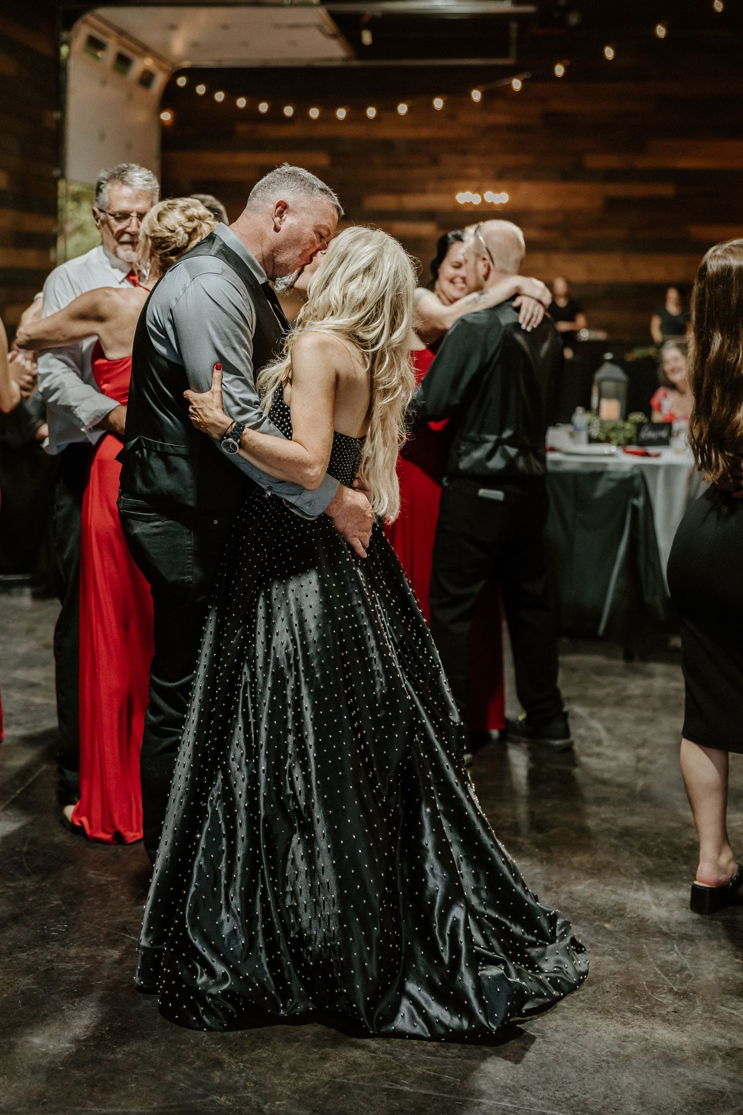 Dancing couples in formal attire under warm lighting at an elegant indoor venue.