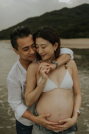 Intimate maternity photo series showing tender moments between expecting parents at a scenic outdoor location.