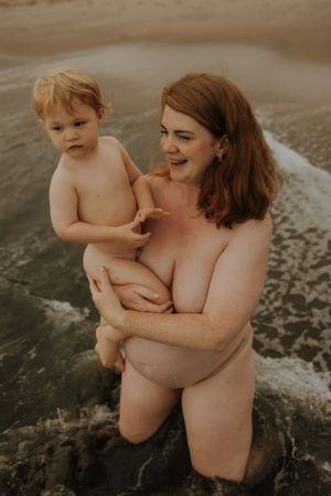 A mother and young child enjoy a peaceful moment together at the beach shore in natural surroundings.