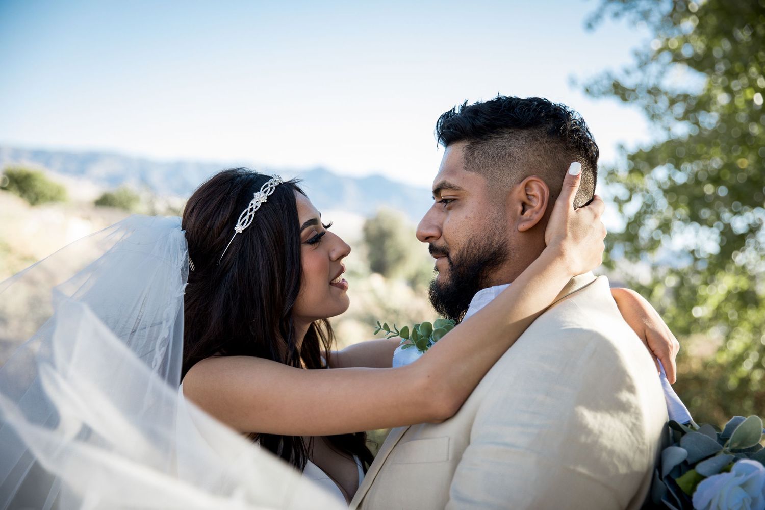 Newlyweds share intimate moment outdoors in formal wedding attire.