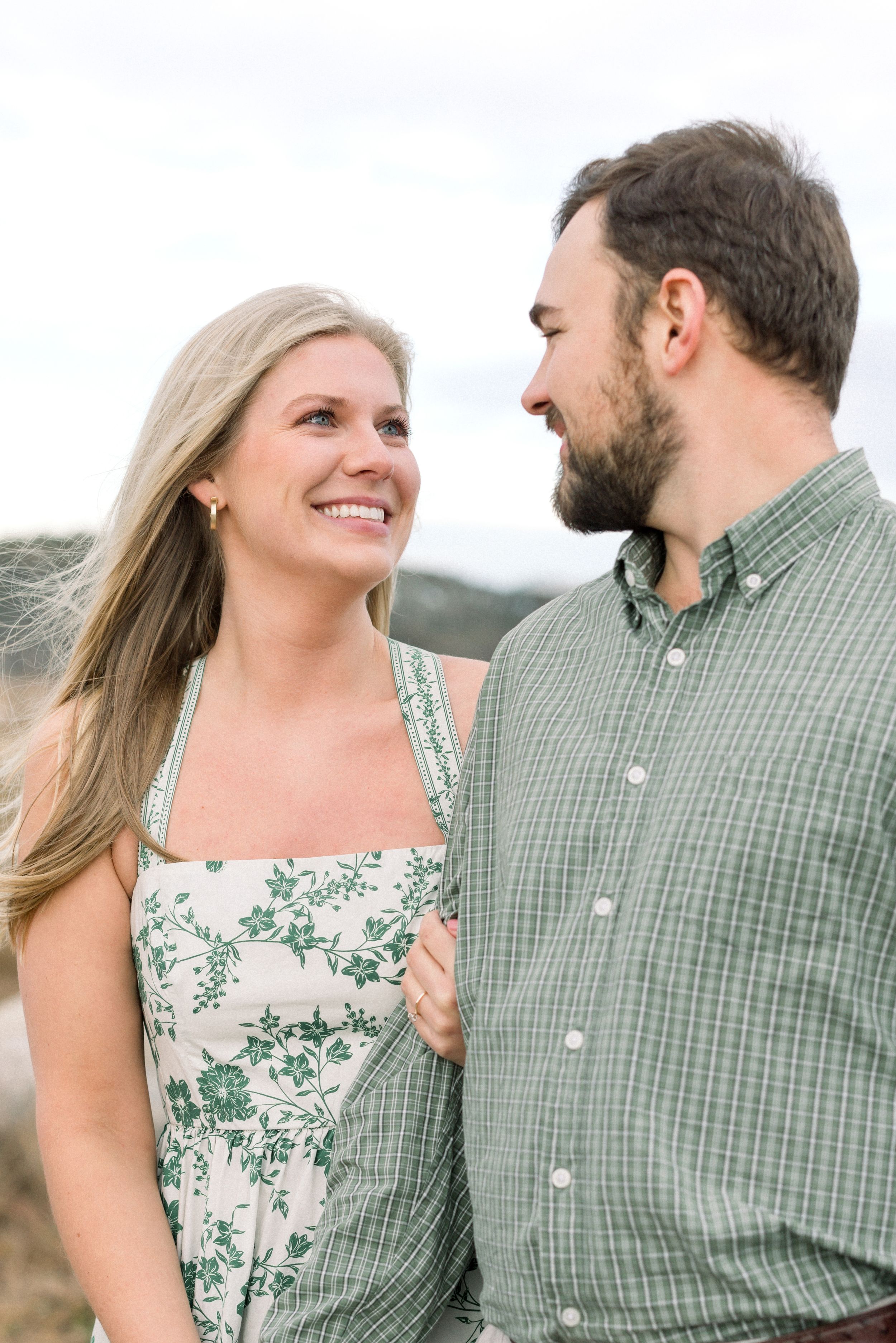 Romantic engagement photo series showing couple in matching green plaid and floral outfits looking lovingly at each other outdoors.