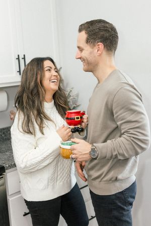 A couple shares a joyful moment while holding drinks in a bright modern kitchen.