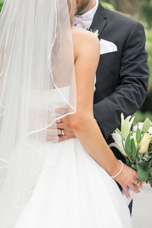 A series of wedding photos showing close-up details of a bride in white dress with veil and groom in black suit.