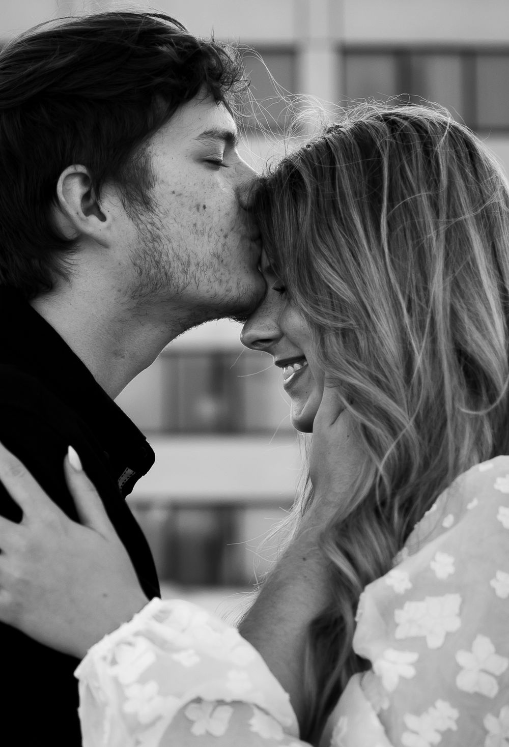 Intimate black and white portrait captures a tender romantic moment between a couple sharing a loving kiss.