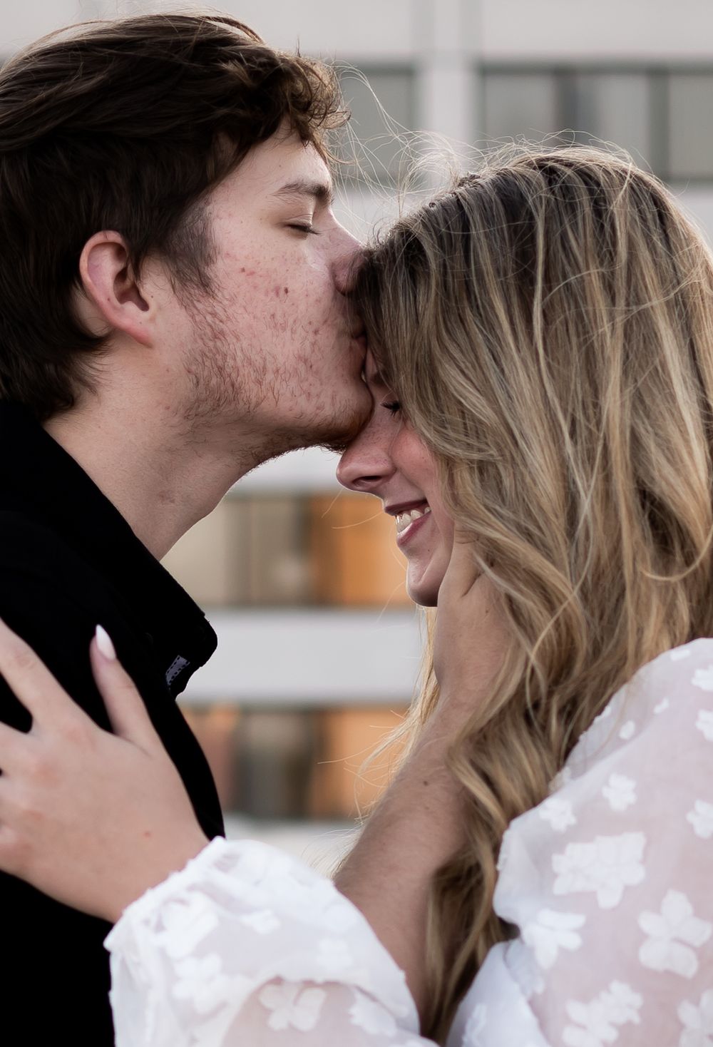 A tender moment between two people sharing a kiss and an embrace, with one wearing a white lace top.