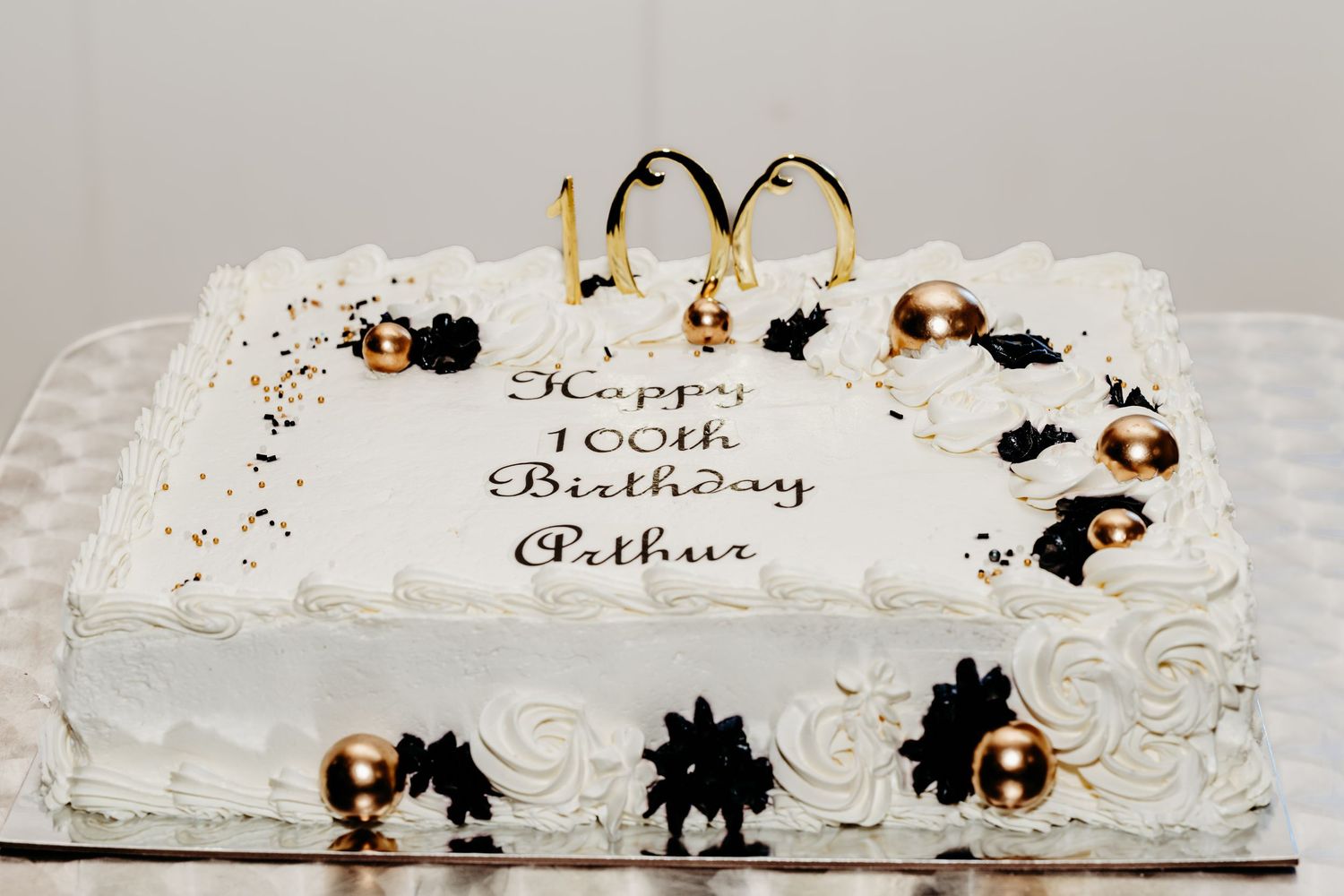 White wedding cake decorated with delicate black silhouettes and golden accents on multiple tiers.