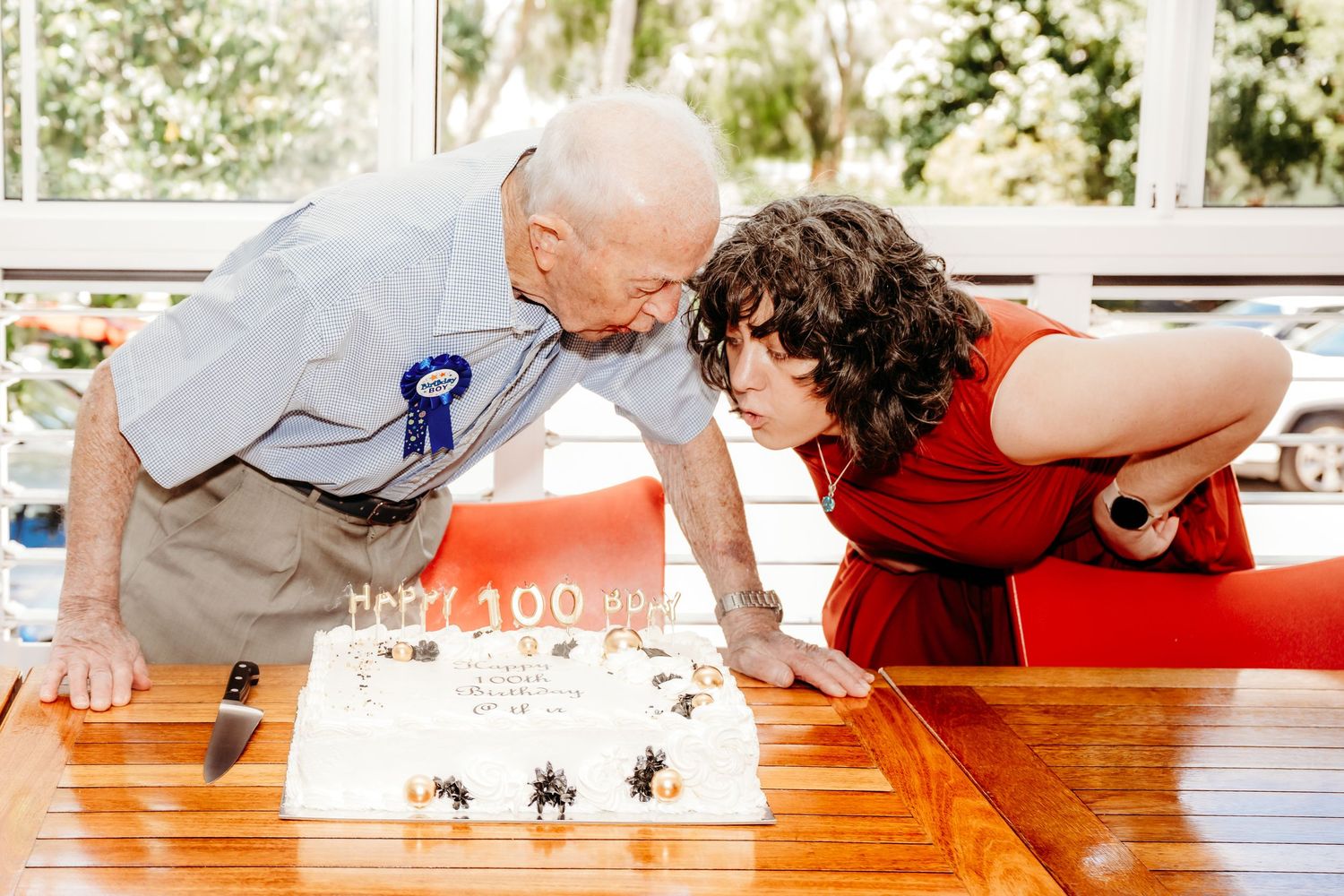 People leaning over a wooden table in a playful pose during what appears to be a casual gathering.