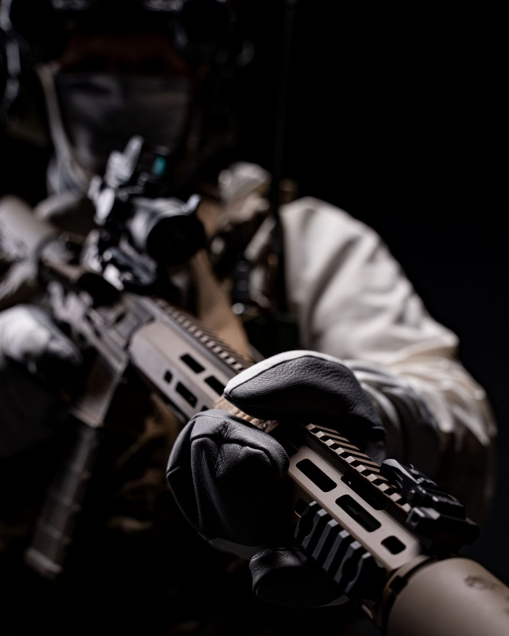 Close-up view of a black tactical rifle with rail system and accessories against dark background.
