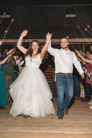 Wedding guests celebrate with a sparkler exit at a rustic venue.