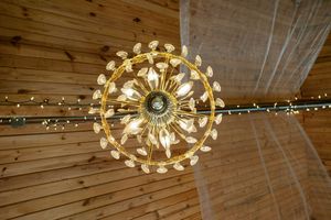 Decorative circular light fixture with multiple bulbs mounted on a wooden ceiling creates warm ambient lighting.