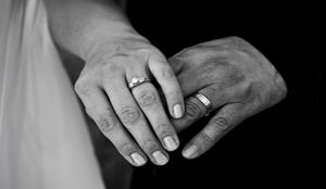 Black and white close-up of hands with wedding rings in a romantic and artistic composition.