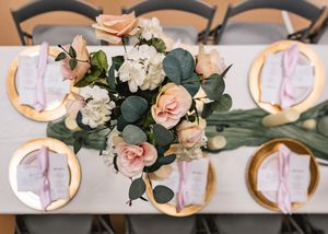Elegant place settings with gold-rimmed plates, eucalyptus leaves, and peach roses create a romantic wedding table decor.