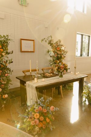 An elegant wedding reception table with floral arrangements and a flowing table runner.