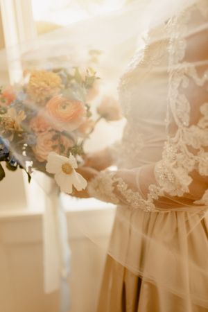 Delicate close-up details of wedding dress lace and floral elements in soft natural light.