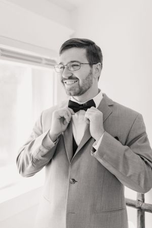 A sequence of shots showing a groom adjusting his black bowtie while getting ready for the wedding ceremony.
