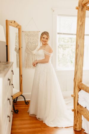 Elegant bridal preparation room with white wedding dresses displayed against rustic wooden beams.