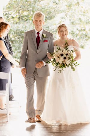 Wedding processional captured in soft natural light on covered porch.