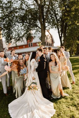 Wedding party celebrates joyfully in an outdoor garden setting during golden hour.