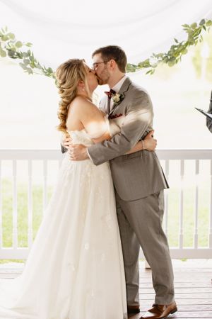 Romantic first look moment on white porch with natural greenery.