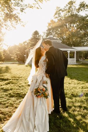 Romantic wedding photos in a sunlit field during golden hour with beautiful backlit composition.