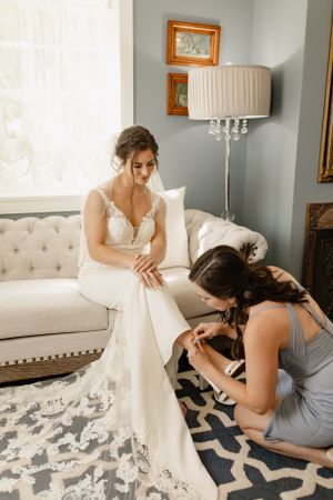 Wedding dress preparation sequence showing delicate detailing and final adjustments in an elegant room setting.