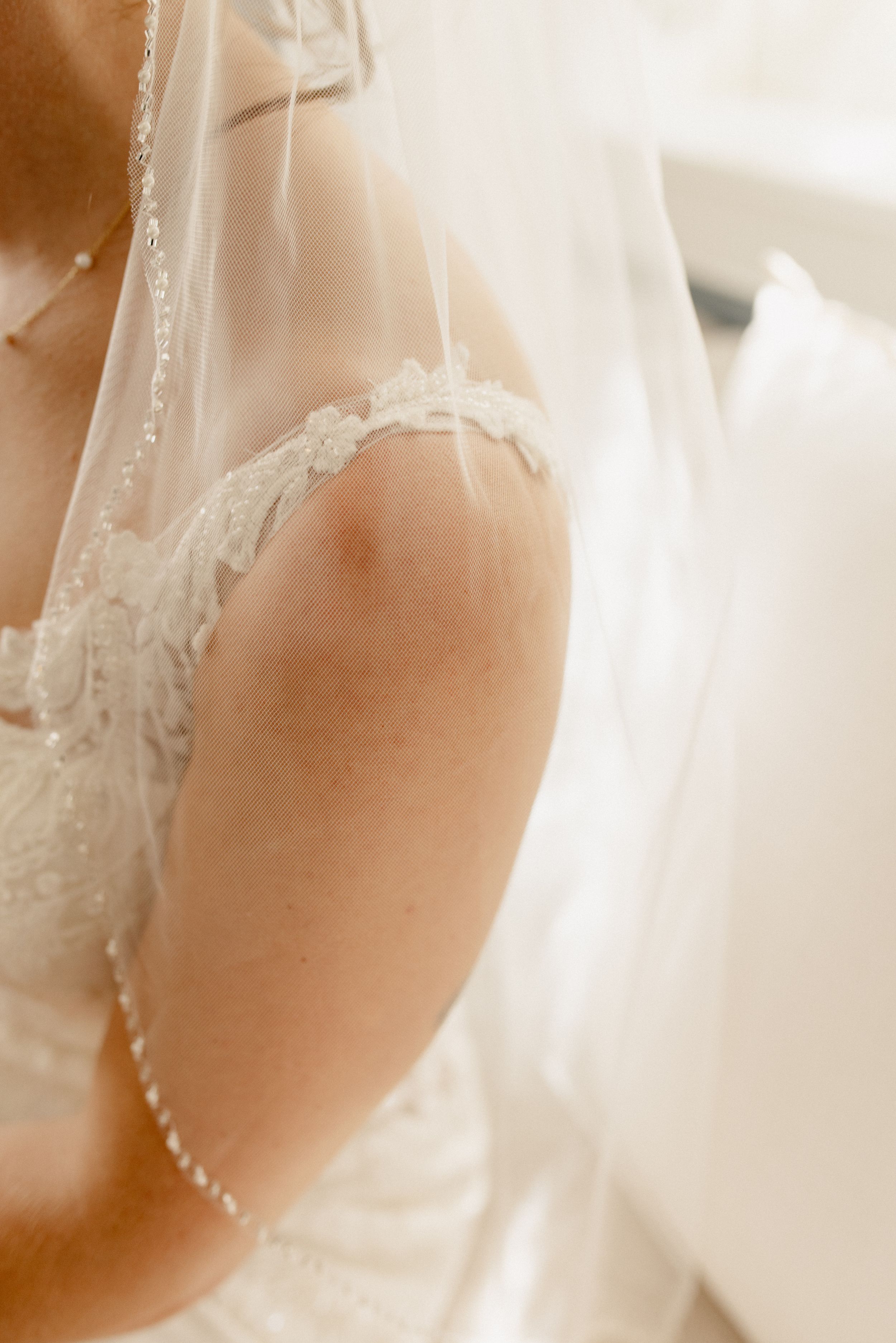 Close-up details of intricate lace and beadwork on a white wedding dress.