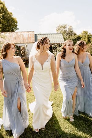 Bridesmaids in light blue dresses walking together outdoors with the bride in white.