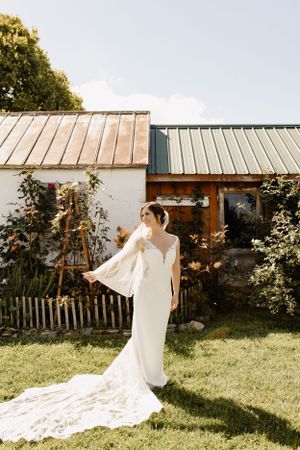 Bride in flowing white dress with long train twirling in a sunlit garden.