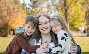 An affectionate outdoor family portrait taken in a sunny autumn park setting.