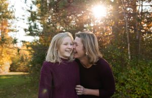 Two people share a tender moment together during golden hour with sunlight streaming through trees.