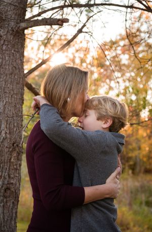 An intimate embrace captured in golden sunlight through autumn trees.