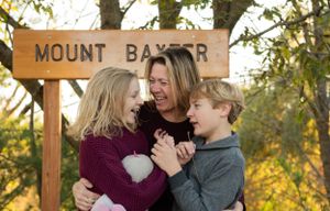 A joyful moment shared under a Mount Baker wooden sign during sunset.