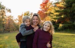 A heartwarming group photo captured during golden hour with fall foliage in the background.